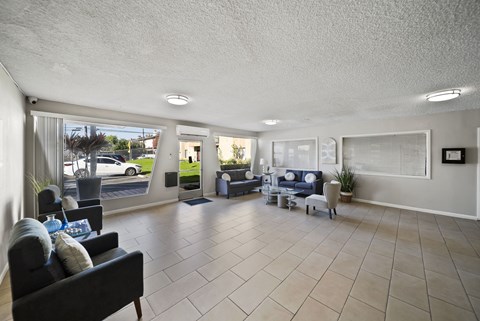 A spacious living room with a black couch and a large window.