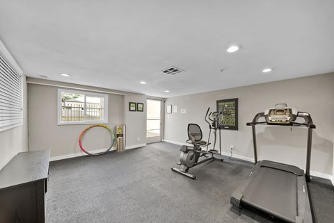 A spacious room with a treadmill, exercise bike, and a chair.