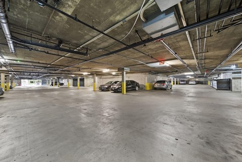 A parking garage with concrete floors and yellow poles.