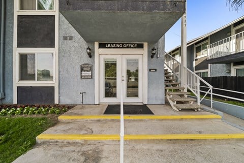 A building with a leasing office entrance has a yellow line painted on the concrete.