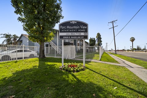 A sign for Parc Mountain View Apartment Homes stands in front of a fence.