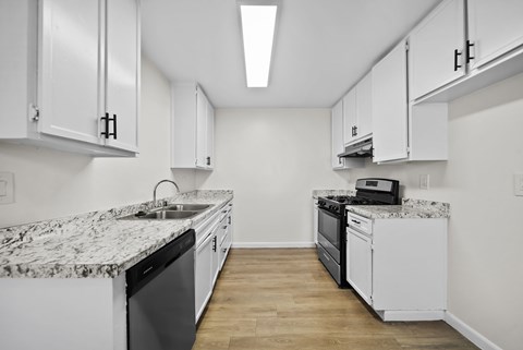 A kitchen with white cabinets and a marble countertop.