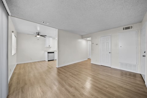 A spacious room with wooden flooring and white walls.