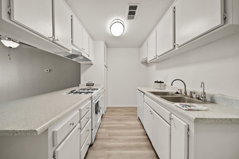 A white kitchen with a sink and a stove.