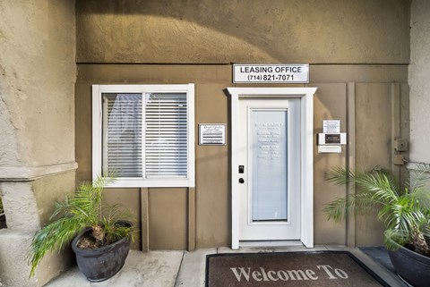 A leasing office with a welcome mat and a door.