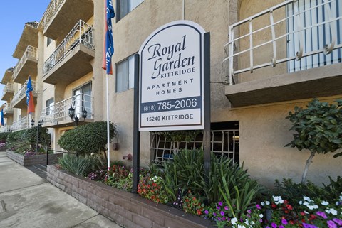 A sign for Royal Garden Apartment Homes is displayed in front of a building.