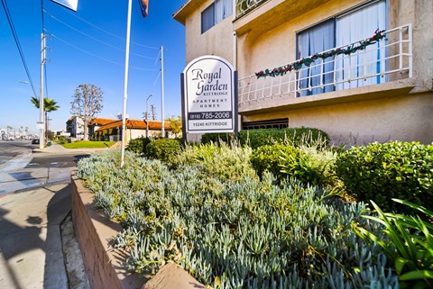 A sign for Royal Garden Apartments stands in front of a building.
