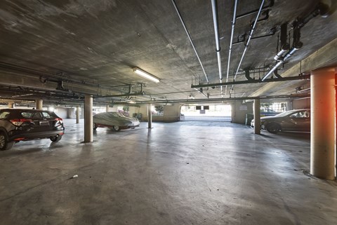 A parking garage with cars parked and a concrete floor.
