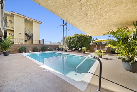 A small pool in a backyard with a building in the background.