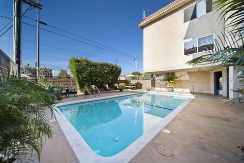 A small pool in a backyard with a house in the background.