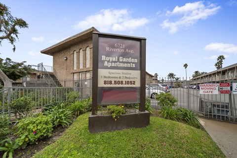 A sign for the Royal Garden Apartments stands in front of a building.