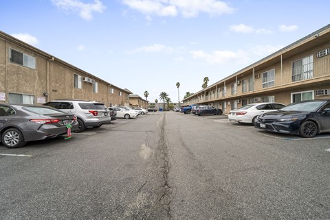 A parking lot with cars parked in front of apartment buildings.