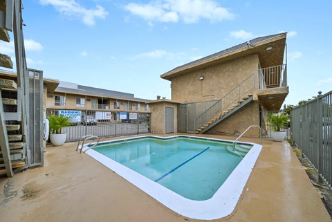 A small pool in a backyard with a staircase leading to a balcony.