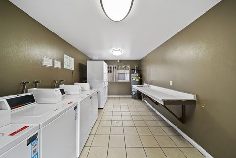 A laundromat with washers and dryers lined up on both sides of the room.