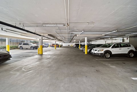A parking garage with cars parked and yellow bollards.