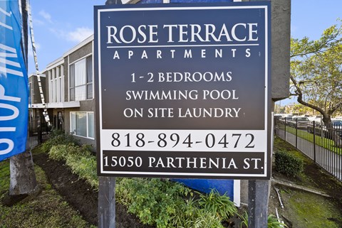 A sign for Rose Terrace Apartments with a swimming pool on site.