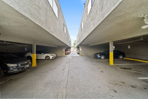 A parking garage with cars parked on both sides of the aisle.