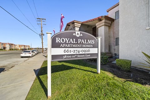 A sign for Royal Palms Apartment Homes stands in front of a building.