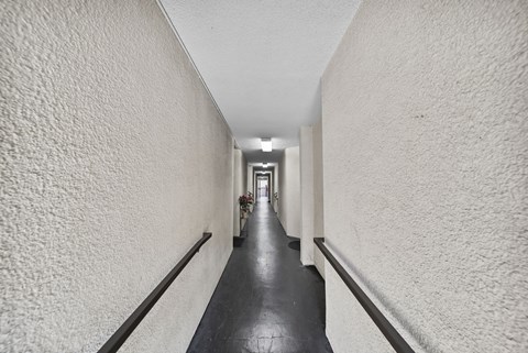 A long hallway with white walls and a black floor.