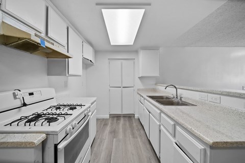 A modern kitchen with white cabinets and a white gas stove.