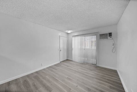 A room with a wooden floor and a window with blinds.