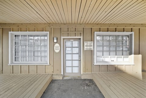 A wooden porch with a door and windows.