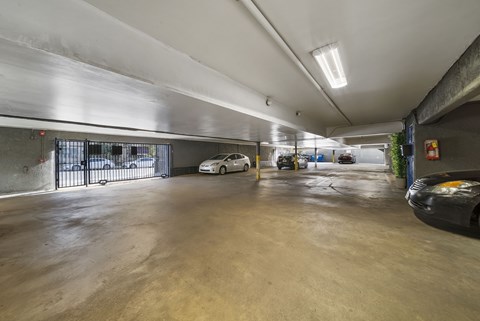 A parking garage with a white car and a black car parked inside.