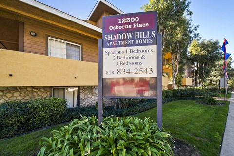 A sign for Shadow Hills Apartment Homes is in front of a building.