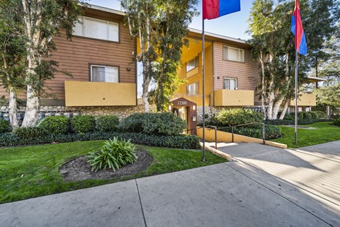 A building with a brown and yellow exterior and a small garden in front.