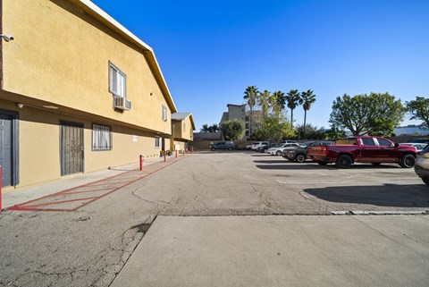 A parking lot with a red car and a yellow building.