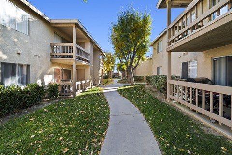 A pathway leads between two buildings with balconies.