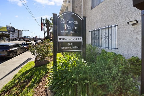 A sign for Sherman Pointe Apartments is in front of a building.