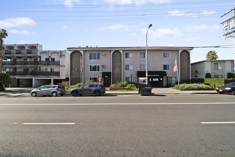 A street view of a residential area with cars parked on the side of the road.