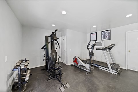 A home gym with a treadmill, elliptical trainer, and a weight machine.