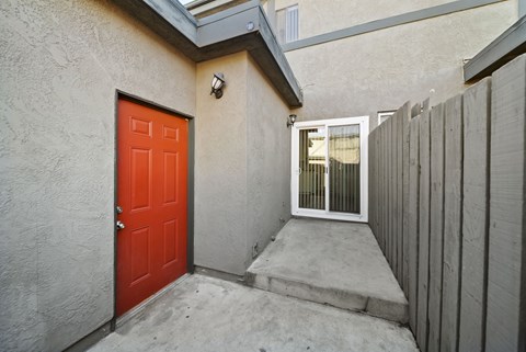 A red door is on the left side of a concrete staircase.