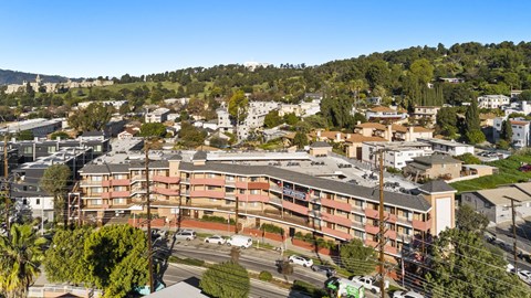A large apartment complex is surrounded by trees and other buildings.
