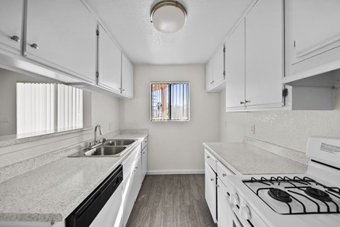 A kitchen with white cabinets and a white stove top oven.