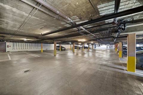 A spacious parking garage with concrete floors and yellow poles.