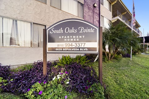 A sign for South Oaks Pointe Apartments stands in front of a building.