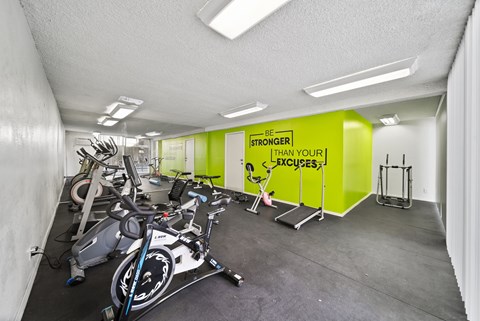 A gym with exercise bikes and a sign that says "Be Stronger Than Your Excuses".