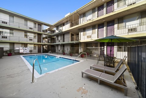 A pool in a courtyard surrounded by apartment buildings.