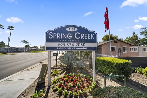 Spring Creek Apartments sign with a red flag on top.