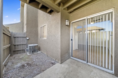 A patio area with a sliding glass door and a wall-mounted air conditioning unit.