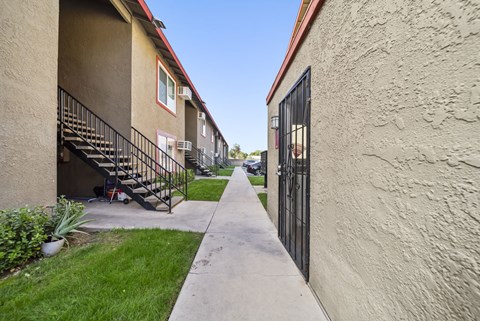 A narrow alley between two buildings with a metal railing on the left.