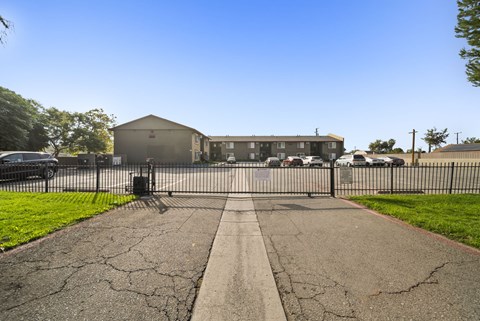 A black gate blocks the entrance to a driveway.