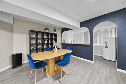 A dining area with a round table and blue chairs.