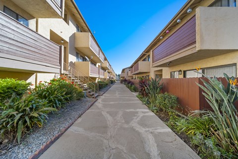 A concrete pathway leads through a row of modern apartment buildings.
