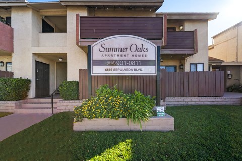 A sign for Summer Oaks Apartment Homes is displayed in front of a building.