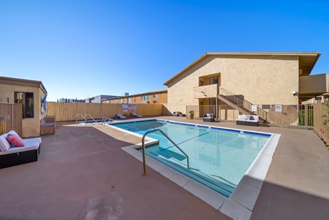 A swimming pool in a backyard with a building in the background.