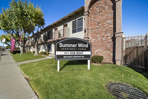 A sign for Summer Wind Apartments is in front of a brick building.